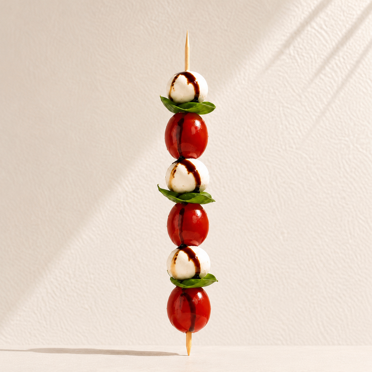Chilled skewer of fresh cheese, tomato, and herbs on a warm wall backdrop